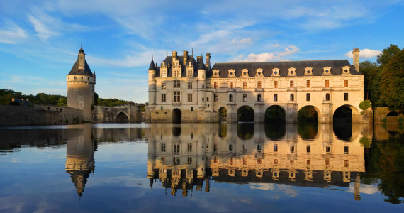 Chateau Chenonceau, a visit on the tour extensions, sitting above still water on a clear day, highlighting the many windows and historical architecture